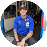 Austin Johnson sits in the open doorway of an ambulance, smiling and wearing a stethoscope around his neck.