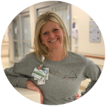 Lindsay Schoem smiling, leaning on a counter with hospital bays in the background.