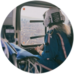 Stephanie Suzadail, wearing a flight suit and helmet, looks out the window of an air ambulance at a cityscape.