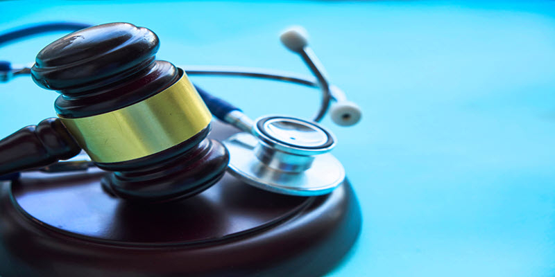 A judge's gavel and a stethoscope rest on a blue surface, symbolizing the intersection of law and healthcare.