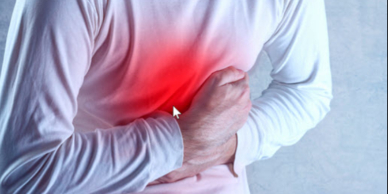 A person in a white shirt clutching their abdomen with one hand, with a red highlight indicating pain or discomfort in the stomach area.