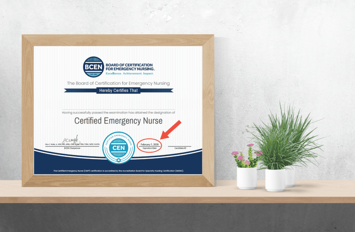 Framed Certified Emergency Nurse certificate on a white desk beside green potted plants, with a red arrow pointing to the certification date.