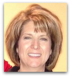 A woman with short, light brown hair smiles at the camera against a plain, light-colored background.