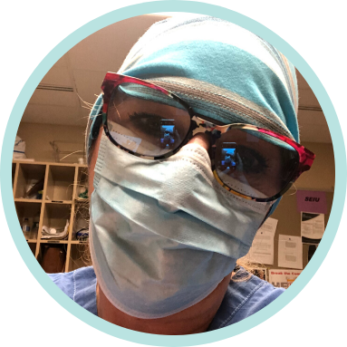 Person wearing a surgical mask, cap, and large sunglasses in a medical setting, with shelves and papers visible in the background.