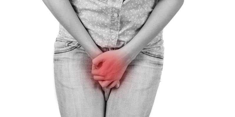 Person holding their lower abdomen with both hands, with a red highlight indicating pain or discomfort in the pelvic area.
