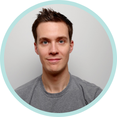 A man with short brown hair and blue eyes is wearing a gray t-shirt and looking at the camera, set against a plain light background with a teal circular border.