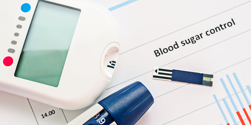 A blood glucose meter, test strip, and lancet pen are placed on a document labeled "Blood sugar control" with charts and graphs partially visible.