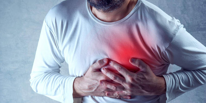 A person in a white shirt clutching their chest with both hands, with a red area highlighting pain or discomfort.