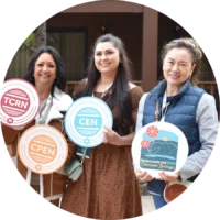 Three women pose outdoors, each holding a sign with various nursing certification logos: TCRN, CPEN, CEN, and BCEN Learn Live 2025 Colorado Springs—an exciting emergency nursing conference for sponsors and exhibitors.