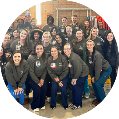 Large group of healthcare workers in gray scrubs posing together for a photo.